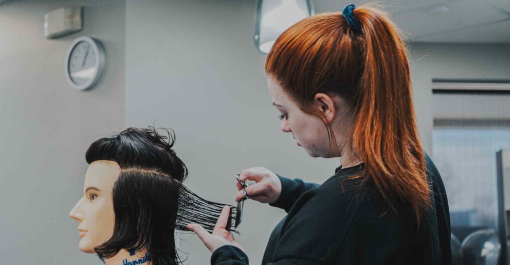 Student cutting a mannequin head's hair